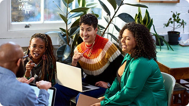 Group discussion around a laptop in an indoor workspace.