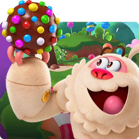 Animierter Yeti aus Candy Crush mit einer großen, bunt verzierten Schokoladenkugel vor einer farbenfrohen Candy-Landschaft.
