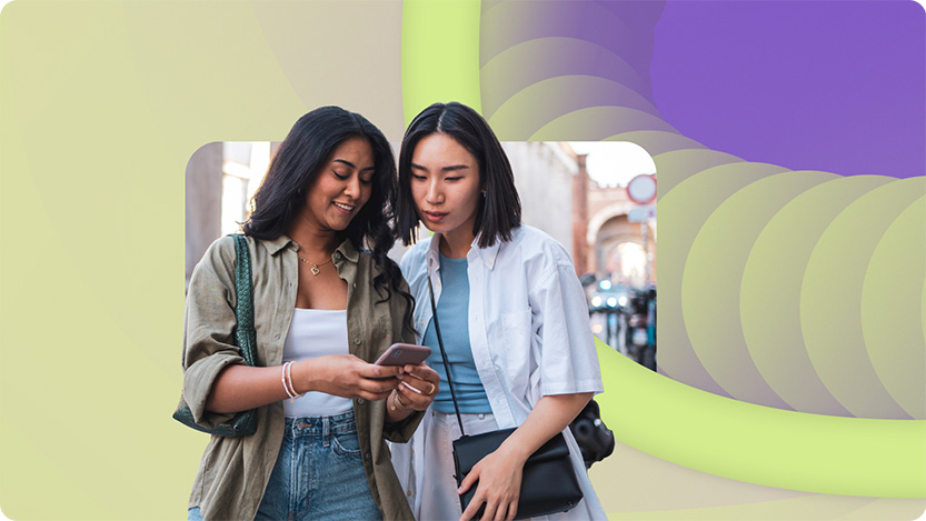 Two friends visiting Milano, Italy, standing outdoors and looking at a smartphone. They are enjoying travel and sightseeing.