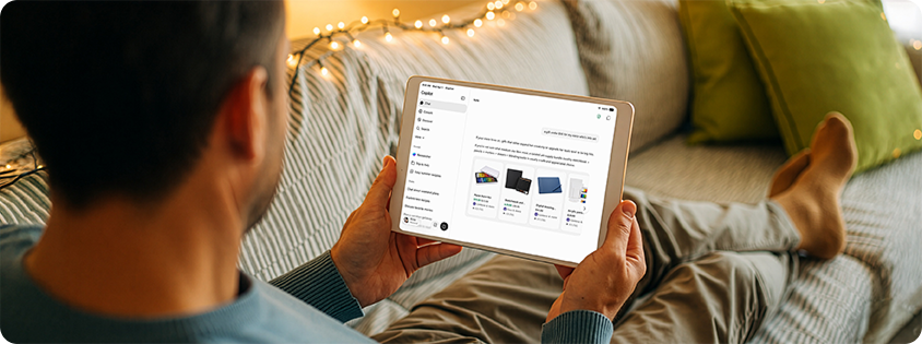  Person relaxing on a sofa at home while using a tablet displaying the Microsoft Copilot experience. The screen shows product recommendations for art materials, illustrating how Copilot helps users discover, compare, and explore products.