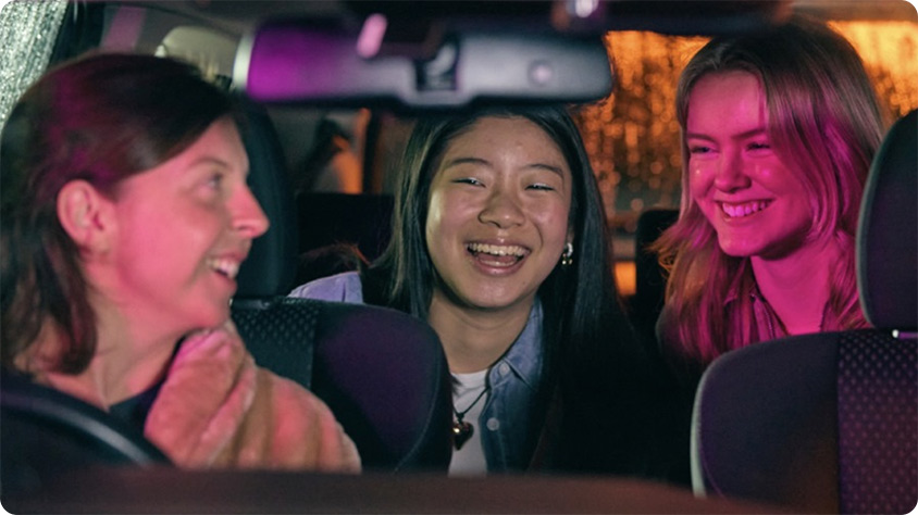 Three people in a car smiling.