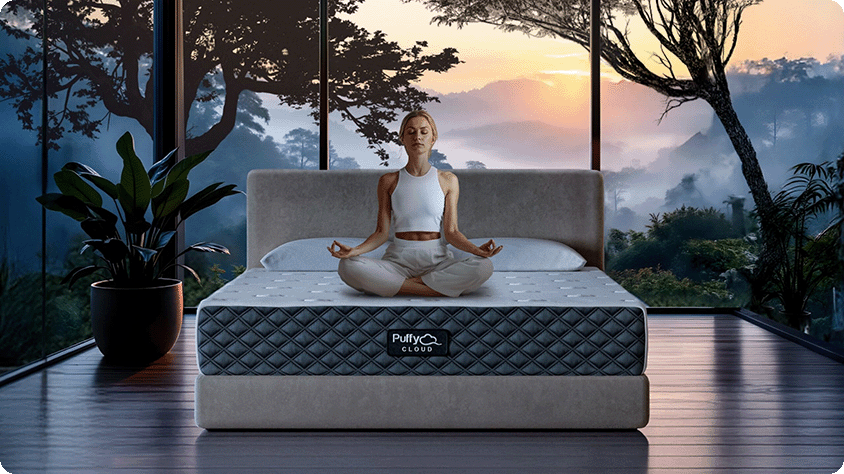 A woman with a calm expression is sitting cross-legged on a luxurious Puffy Cloud mattress, meditating with her hands in a mudra position.